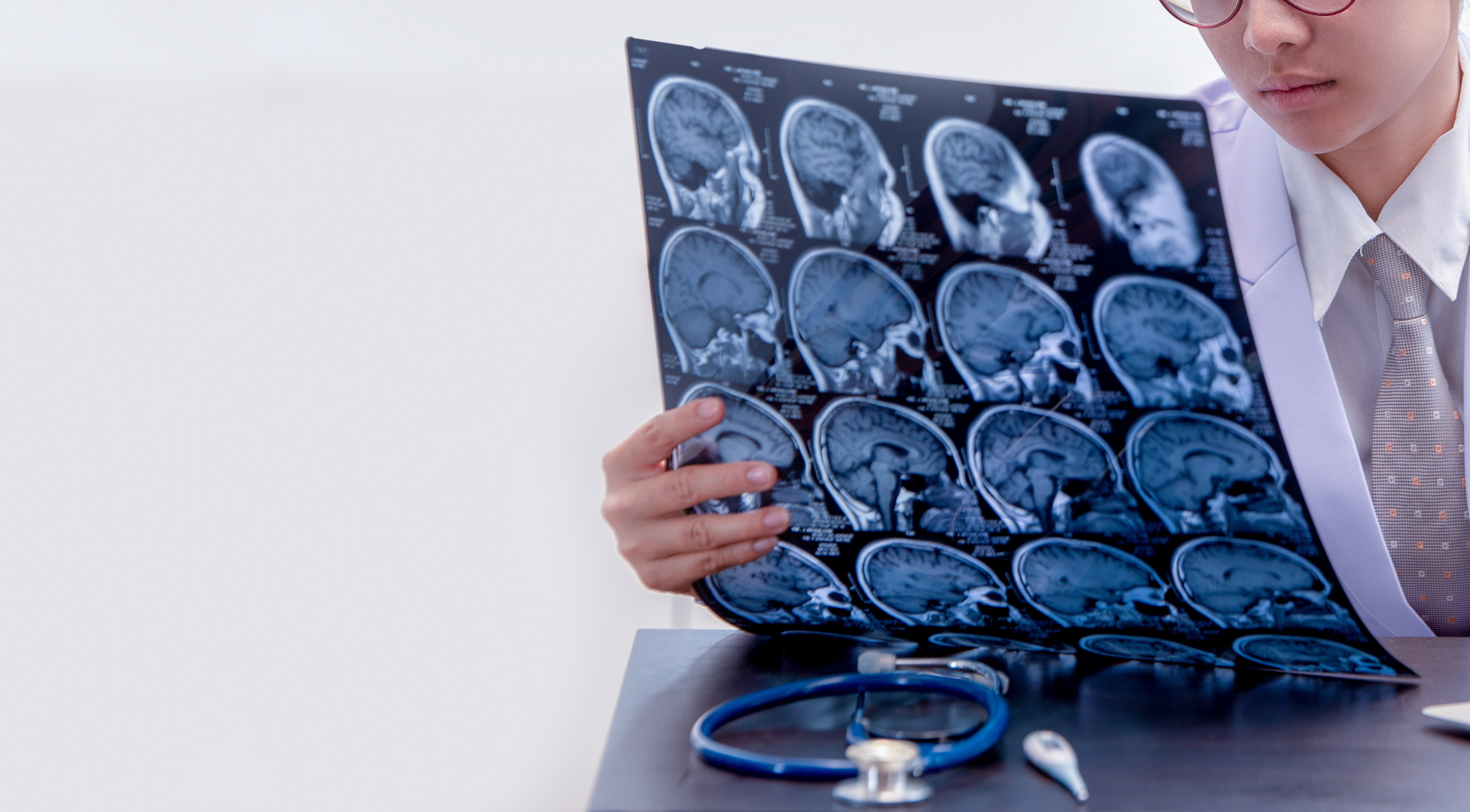 young female doctor holding MRI or CT scan picture, doctor in uniform sitting in working room and holding X-ray picture for diagnosis brain injury or cerebrovascular accident of patient